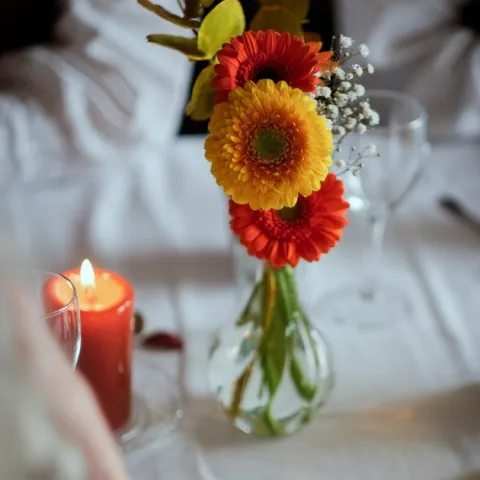 en vase med blomster og et lys